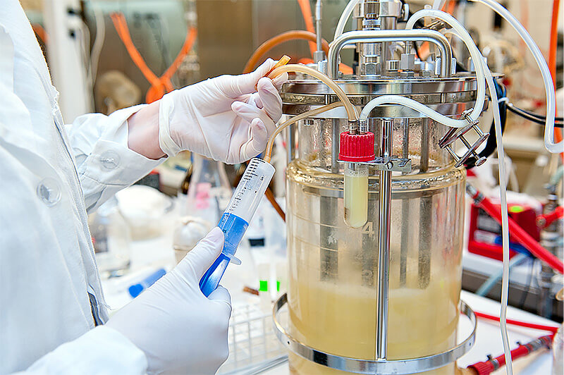 Close-up photo of lab scientist working with a calibrated bioreactor. 